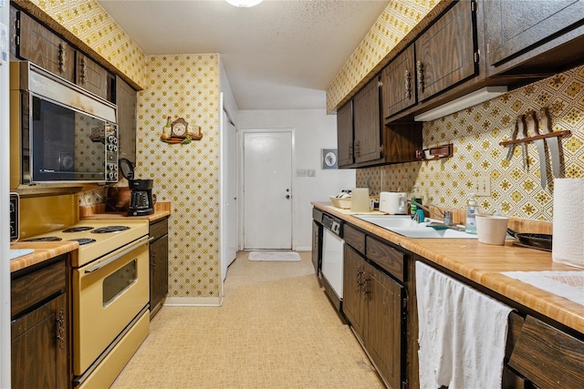 kitchen with a textured ceiling, dark brown cabinetry, sink, white electric stove, and dishwasher