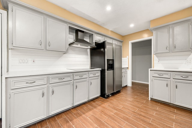 kitchen with tasteful backsplash, stainless steel fridge, black electric stovetop, and wall chimney exhaust hood