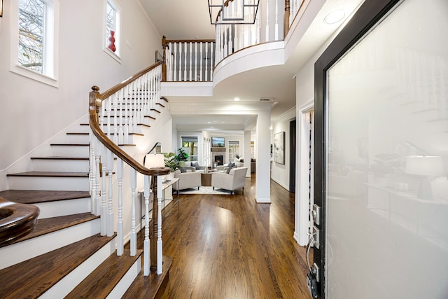 entryway featuring ornamental molding, dark wood-type flooring, and a towering ceiling