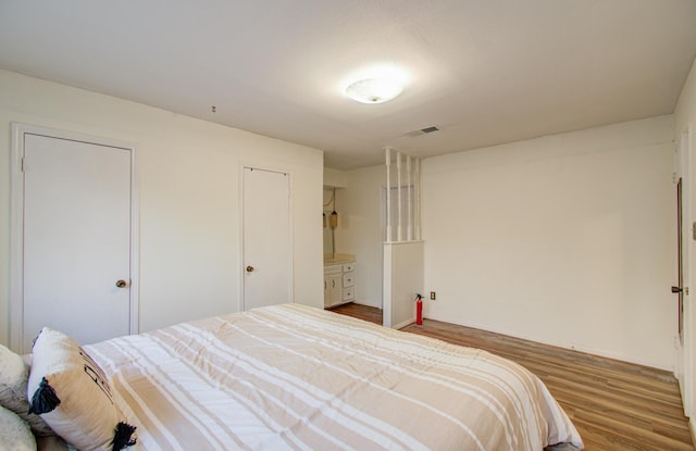 bedroom with wood-type flooring and ensuite bath