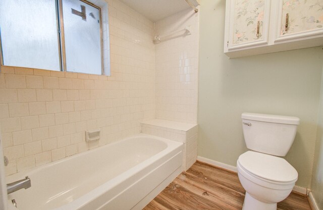 bathroom featuring tiled shower / bath, wood-type flooring, and toilet