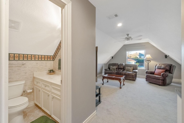 bathroom with vanity, toilet, ceiling fan, and vaulted ceiling