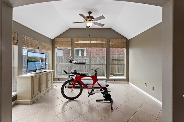 workout area featuring ceiling fan, light tile patterned floors, and vaulted ceiling