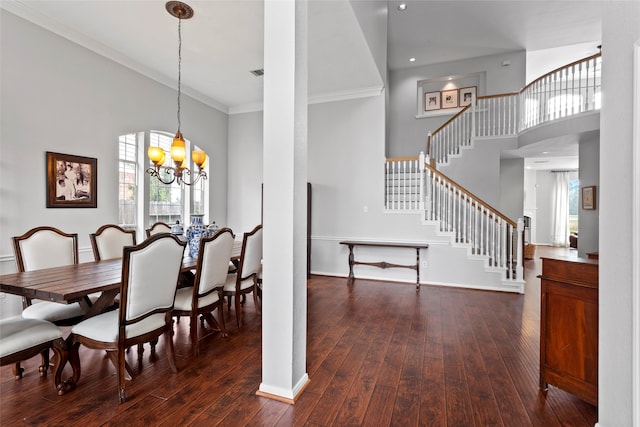 dining room featuring a notable chandelier, dark hardwood / wood-style floors, ornamental molding, and a towering ceiling