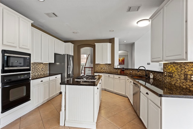 kitchen featuring appliances with stainless steel finishes, sink, light tile patterned floors, white cabinets, and a kitchen island