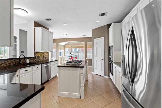 kitchen featuring white cabinets, sink, light tile patterned floors, a kitchen island, and stainless steel appliances