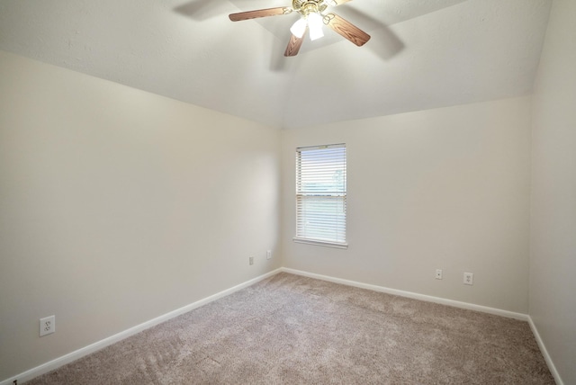 empty room featuring ceiling fan, vaulted ceiling, and carpet