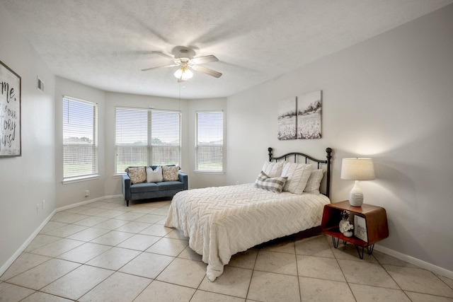 bedroom featuring ceiling fan, light tile patterned floors, and a textured ceiling