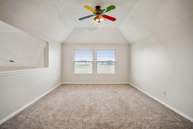 empty room with ceiling fan, vaulted ceiling, a textured ceiling, and carpet