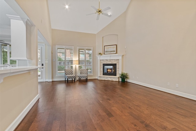 unfurnished living room with a fireplace, high vaulted ceiling, ceiling fan, and dark wood-type flooring