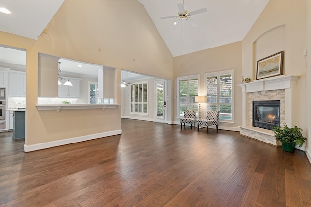 unfurnished living room featuring high vaulted ceiling, a stone fireplace, ceiling fan, and dark wood-type flooring