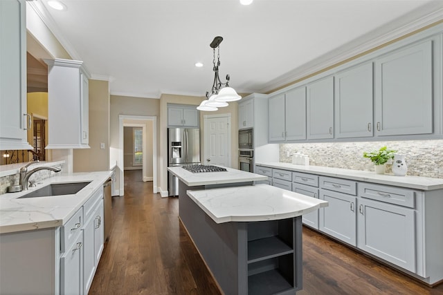 kitchen with light stone countertops, sink, hanging light fixtures, stainless steel appliances, and a kitchen island