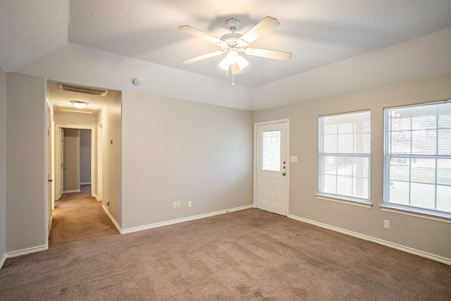 empty room featuring lofted ceiling, a tray ceiling, light colored carpet, and ceiling fan