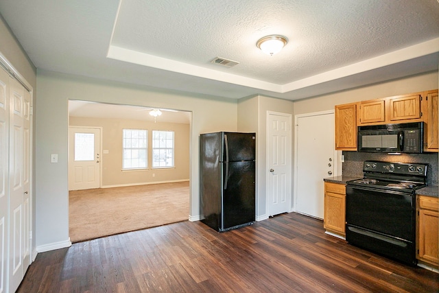 kitchen with dark hardwood / wood-style flooring, a tray ceiling, black appliances, and a textured ceiling