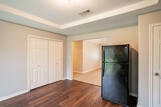 kitchen with black refrigerator, dark wood-type flooring, and a textured ceiling