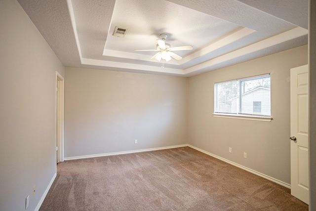 carpeted empty room featuring ceiling fan and a tray ceiling