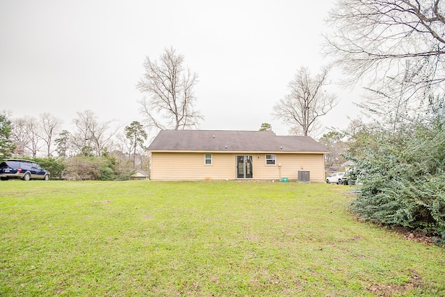 back of property with a yard and central AC