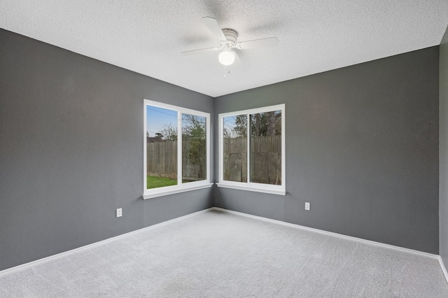 carpeted empty room featuring ceiling fan and a textured ceiling