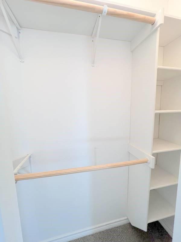 walk in closet with dark carpet