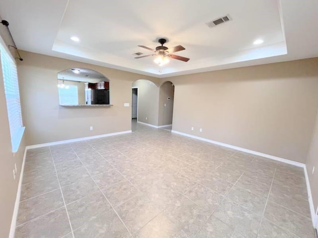 empty room featuring ceiling fan and a raised ceiling