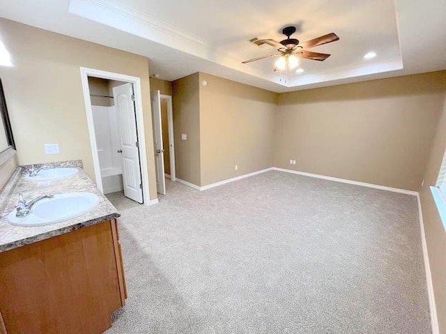 interior space featuring a tray ceiling, ceiling fan, light colored carpet, and sink