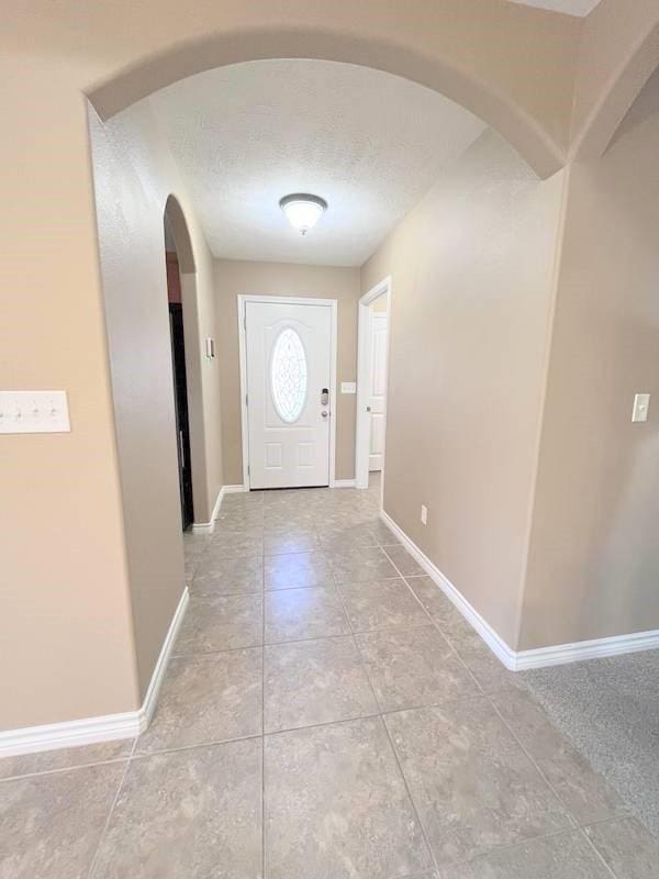 doorway to outside featuring light tile patterned flooring and a textured ceiling