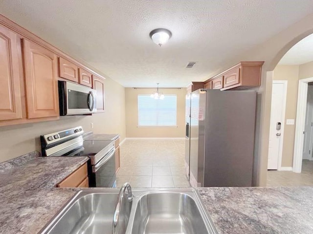 kitchen featuring appliances with stainless steel finishes, a textured ceiling, sink, decorative light fixtures, and a notable chandelier