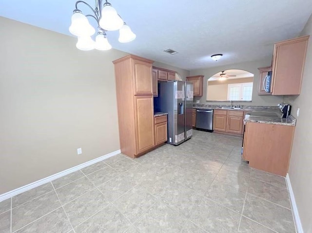 kitchen with sink, hanging light fixtures, light stone counters, ceiling fan with notable chandelier, and appliances with stainless steel finishes