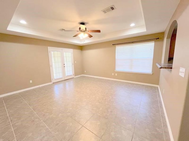 tiled spare room featuring ceiling fan, french doors, and a tray ceiling