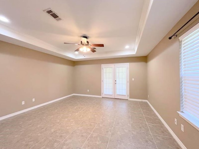 spare room featuring french doors, a wealth of natural light, a tray ceiling, ceiling fan, and light tile patterned floors