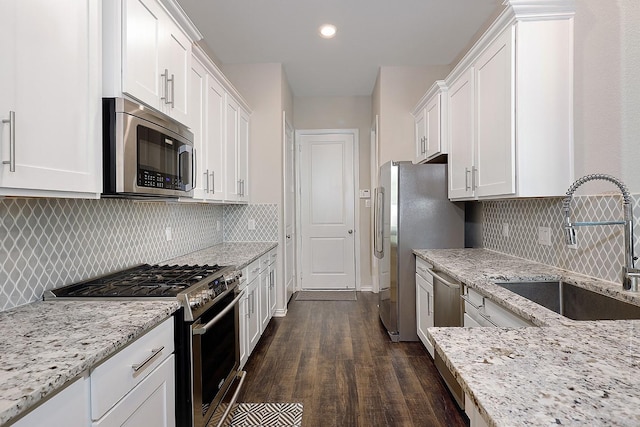 kitchen featuring light stone countertops, stainless steel appliances, sink, dark hardwood / wood-style floors, and white cabinetry