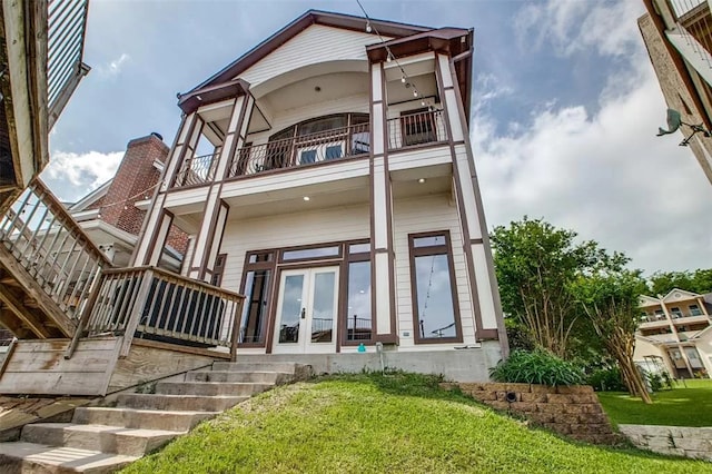 back of property featuring a lawn, french doors, and a balcony