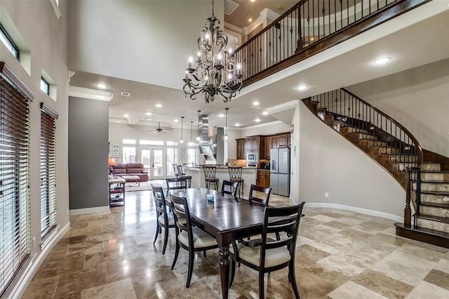 dining room with ceiling fan with notable chandelier, a high ceiling, and ornamental molding