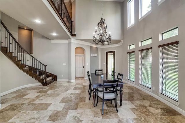 dining area with crown molding, a towering ceiling, and a chandelier