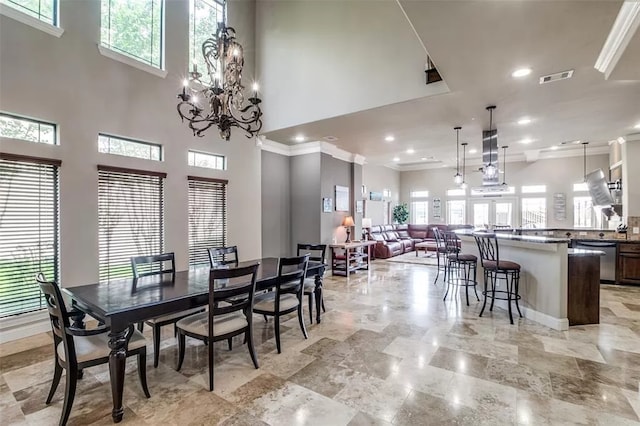 dining space featuring a towering ceiling, an inviting chandelier, and ornamental molding