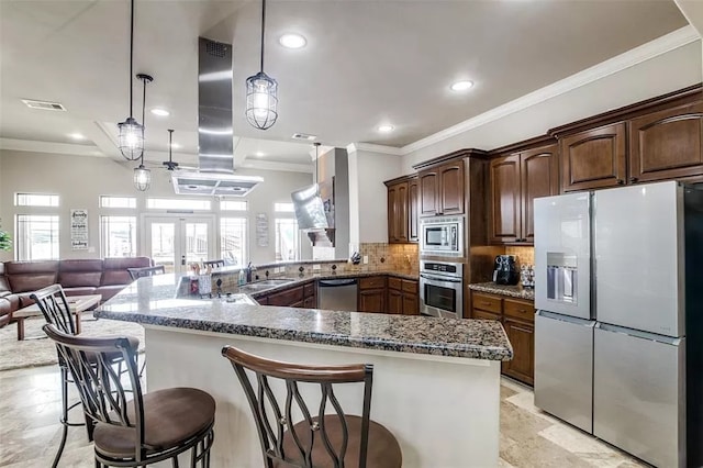 kitchen with a kitchen bar, tasteful backsplash, stainless steel appliances, sink, and hanging light fixtures