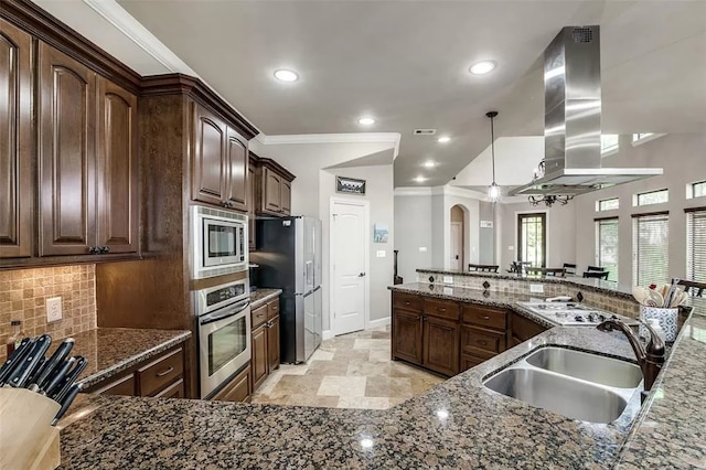 kitchen with dark stone counters, dark brown cabinets, island range hood, stainless steel appliances, and sink