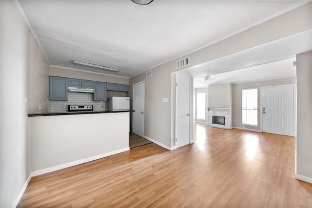 unfurnished living room featuring ceiling fan, ornamental molding, a premium fireplace, and light wood-type flooring