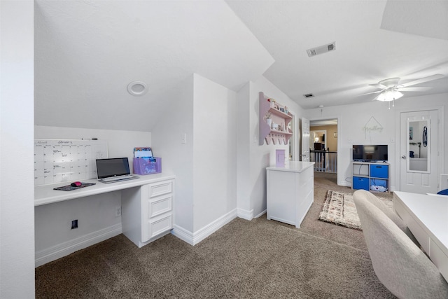 unfurnished office featuring vaulted ceiling, ceiling fan, built in desk, and light colored carpet