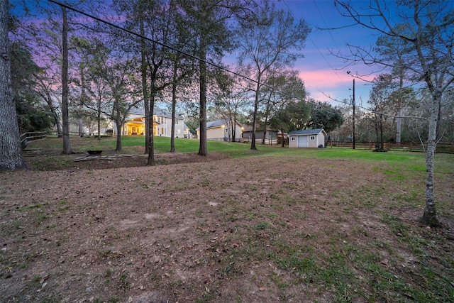 yard at dusk featuring a storage unit