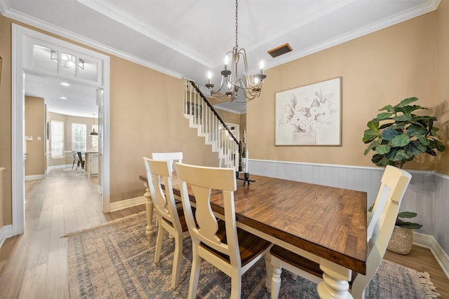 dining room featuring a tray ceiling, ornamental molding, and light wood-type flooring