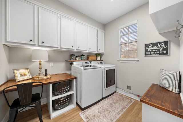 washroom with cabinets, washing machine and clothes dryer, and light hardwood / wood-style floors