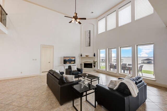 tiled living room featuring a water view, ceiling fan, and a towering ceiling