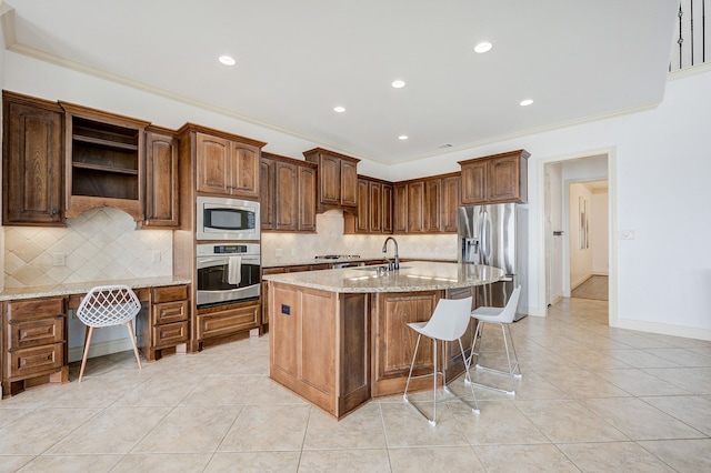 kitchen featuring decorative backsplash, ornamental molding, stainless steel appliances, light tile patterned floors, and a center island with sink