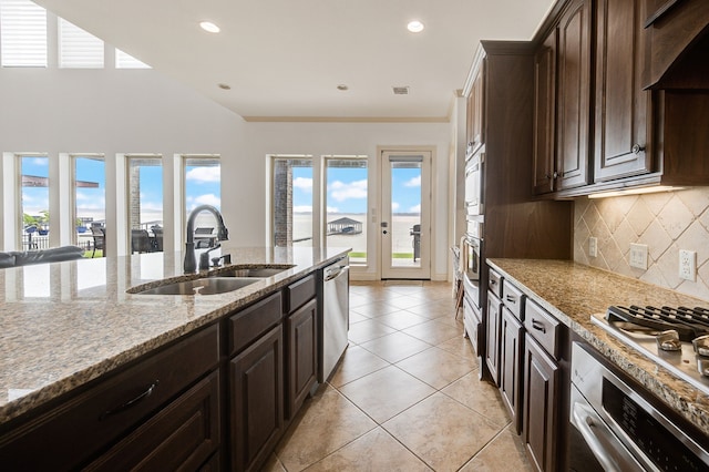 kitchen with light stone countertops, dark brown cabinetry, stainless steel appliances, and sink