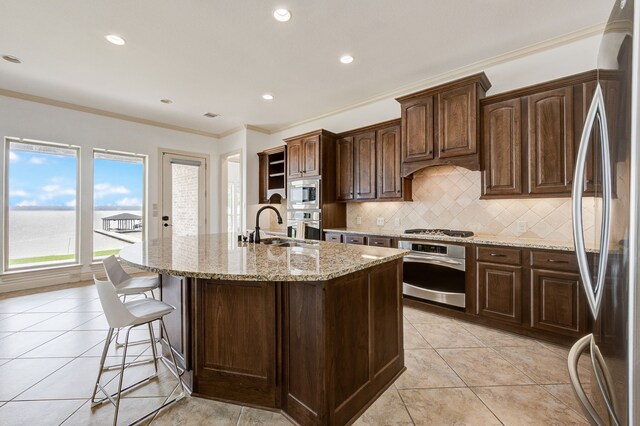 kitchen featuring backsplash, a center island with sink, sink, crown molding, and stainless steel appliances