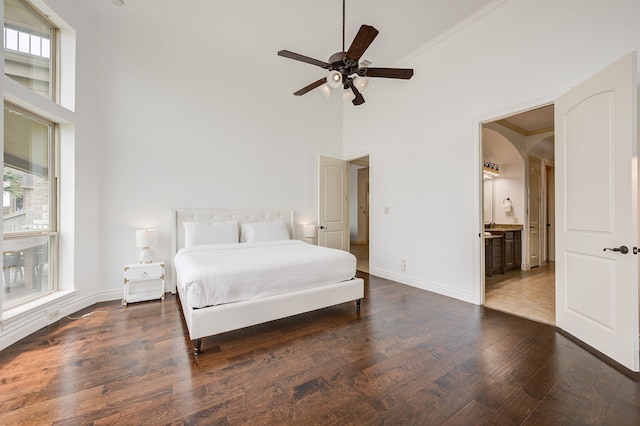 bedroom featuring multiple windows, dark hardwood / wood-style flooring, ensuite bath, and ceiling fan