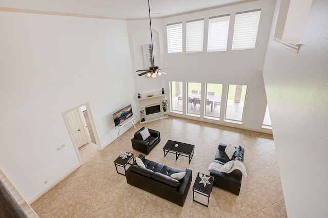 tiled living room featuring ceiling fan, a towering ceiling, and crown molding