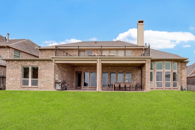 rear view of property featuring a balcony and a yard