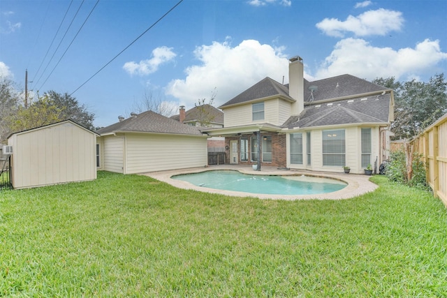 rear view of house with a fenced in pool, a patio area, a yard, and a storage shed